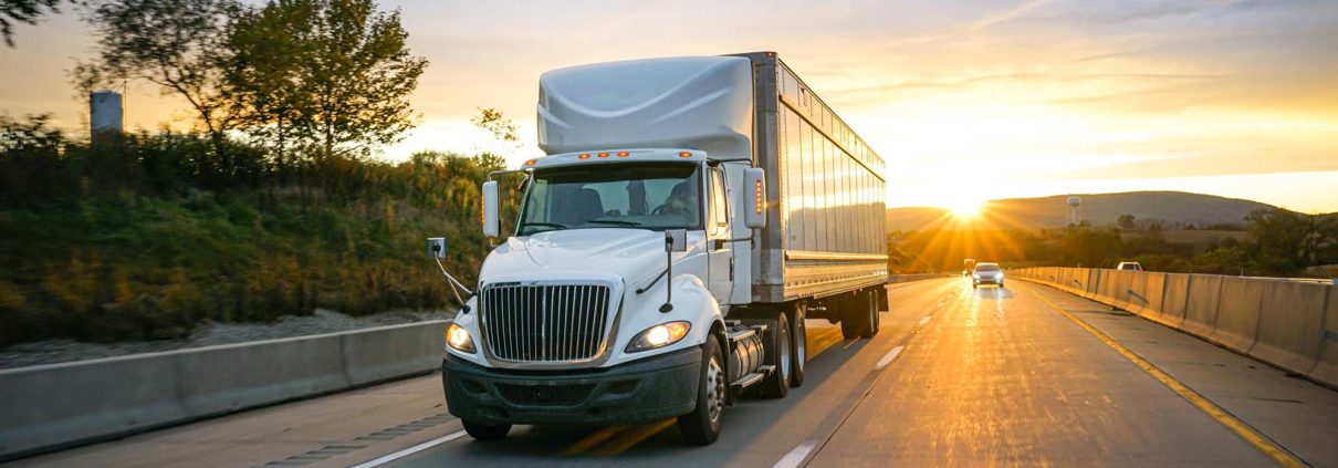 Semi truck driving down the highway at sunset