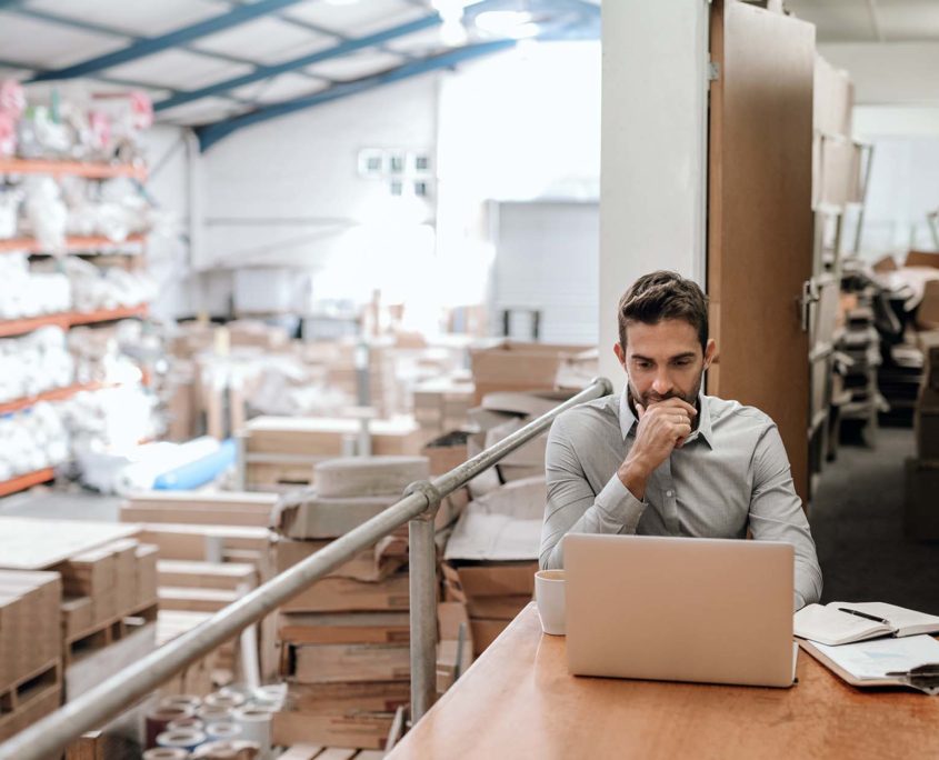 Warehouse manager sitting on laptop at desk