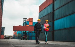 Image of two workers walking through a shipping container yard