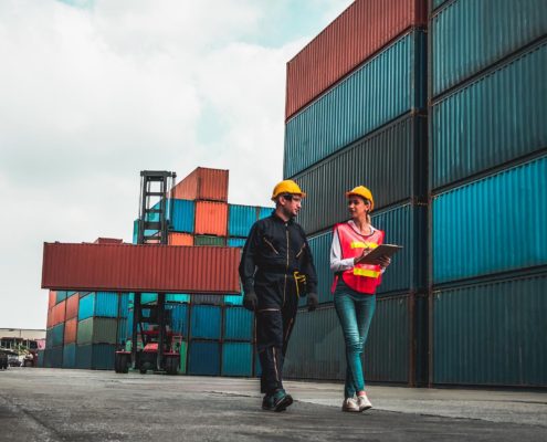Image of two workers walking through a shipping container yard
